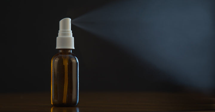 A small aromatherapy spray bottle dispersing a visible mist of essential oils into the surrounding environment.