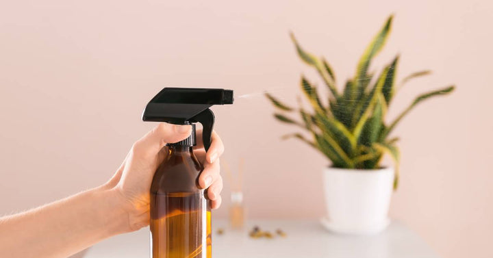  A woman's hand spraying a bottle filled with essential oils around her surrounding area to freshen up the environment.